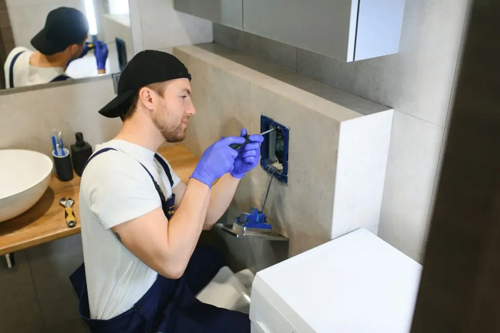 Professional plumber working with toilet bowl in bathroom